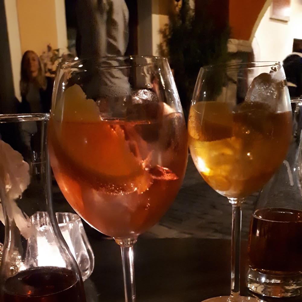 Two glasses of cocktails with ice and a slice of orange.